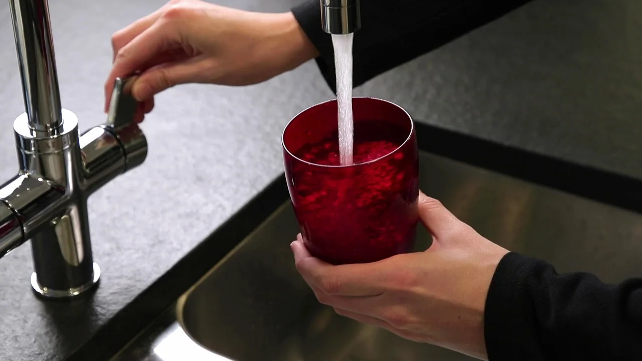 Filling a glass with water before placing an appliance thermometer in it to measure refrigerator temperature