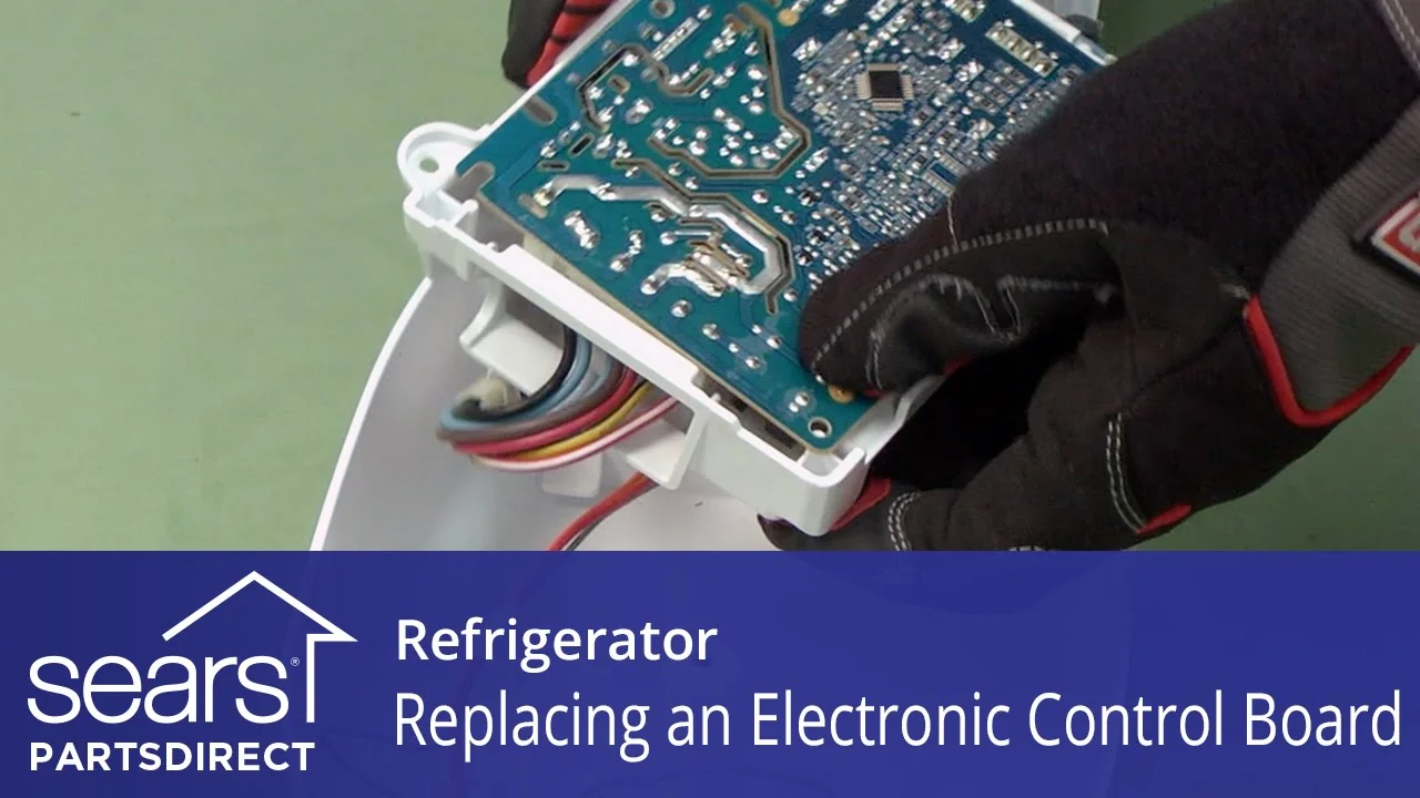 Gloved technician holding an electronic refrigerator control board during replacement